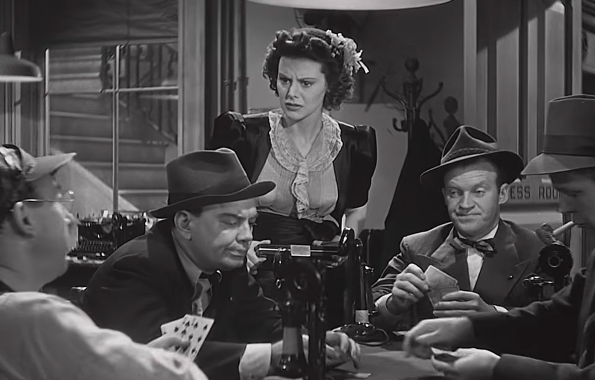 Hildy Johnson standing among male reporters in the press room